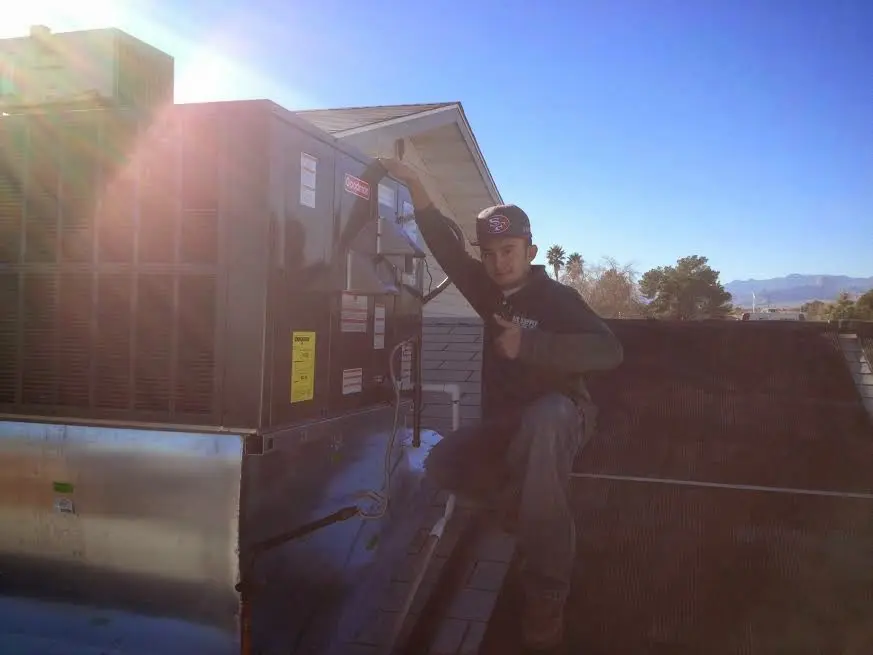 HVAC technician performing Heat Pump Repair on a rooftop unit in Warwick